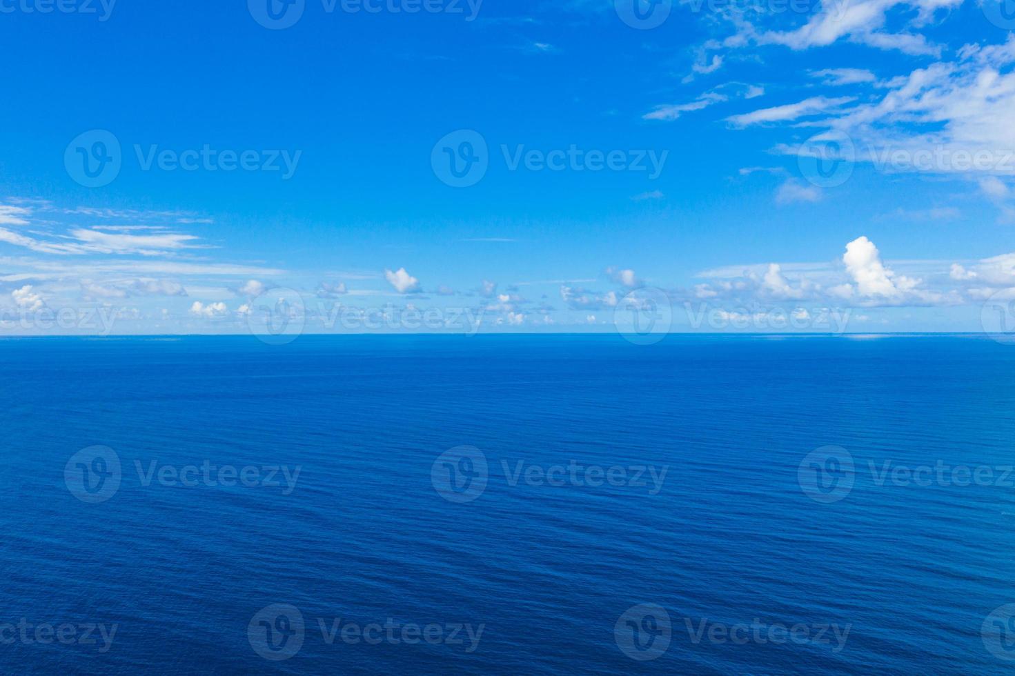 Wide aerial panorama of deep blue ocean. Relaxing minimalistic seascape with small fluffy clouds. Idyllic nature scenic drone view. Endless sea horizon, tranquil view photo