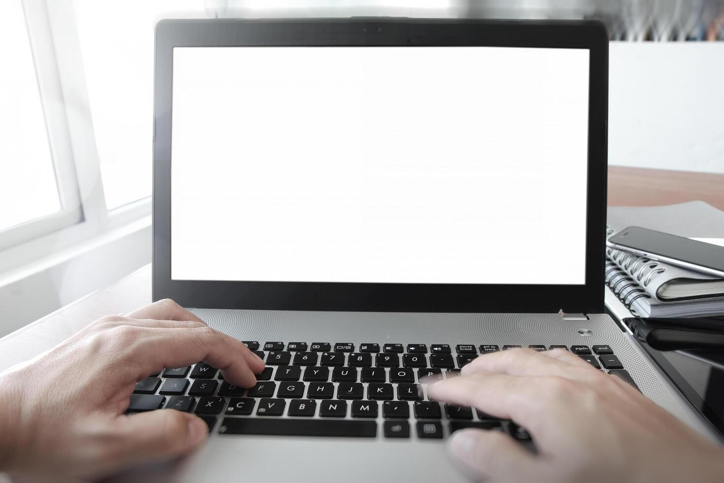 Cerca de la mano del hombre de negocios trabajando en la computadora portátil en el escritorio de madera como concepto foto