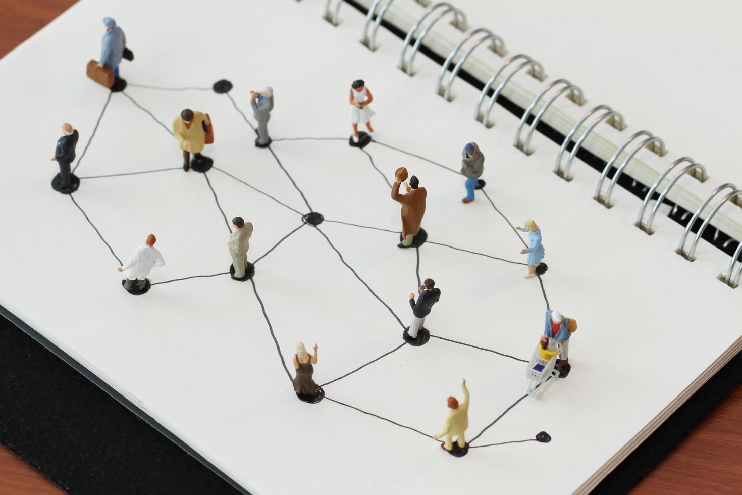primer plano de personas en miniatura con diagrama de red social en un cuaderno abierto en un escritorio de madera como concepto de medios sociales foto