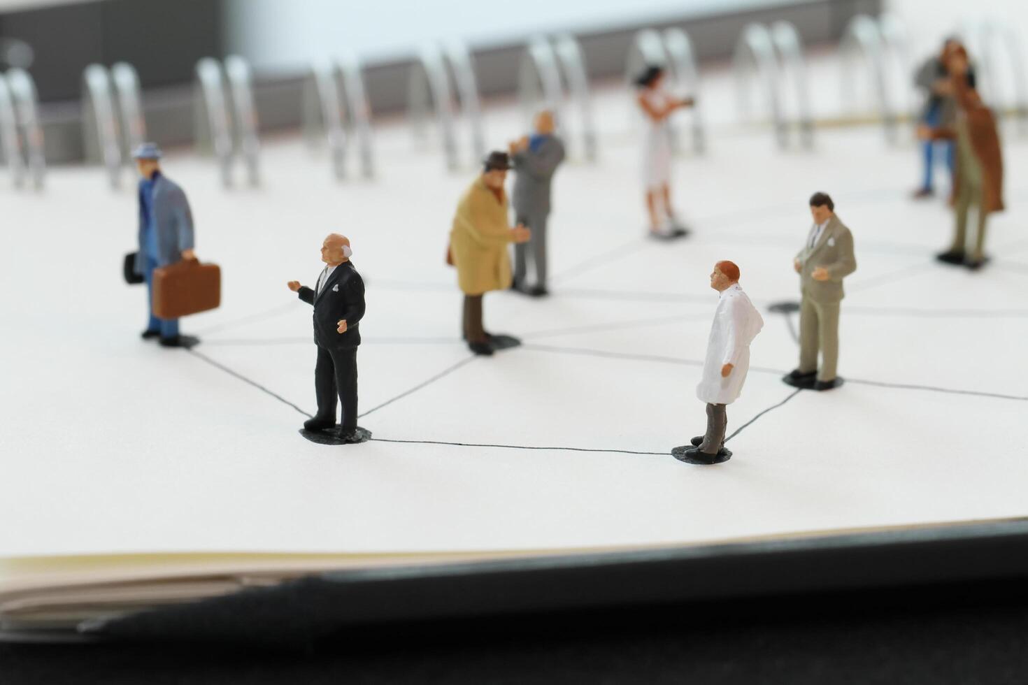 close up of miniature people with social network diagram on open notebook on wooden desk as social media concept photo