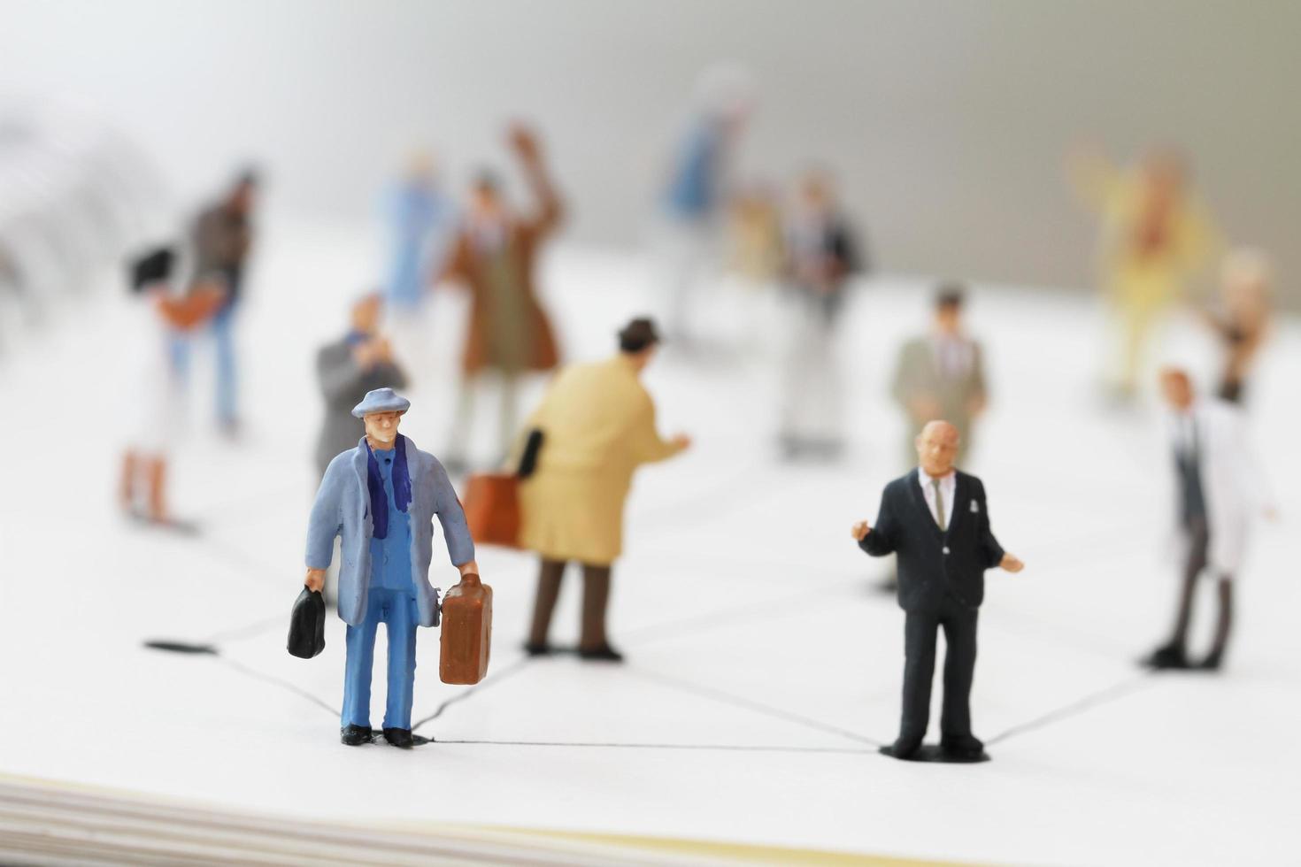 close up of miniature people with social network diagram on open notebook on wooden desk as social media concept photo