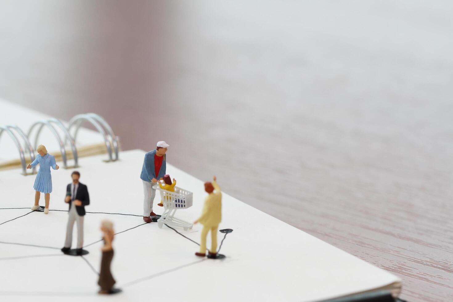 close up of miniature people with social network diagram on open notebook on wooden desk as social media concept photo