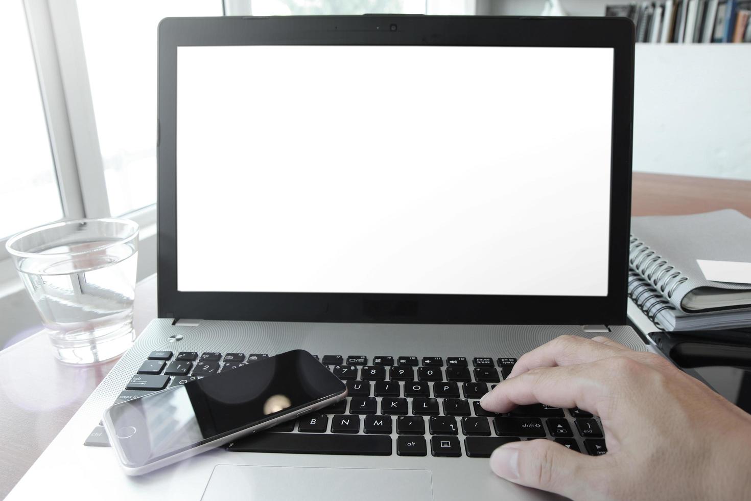 Cerca de la mano del hombre de negocios trabajando en la computadora portátil en el escritorio de madera como concepto foto