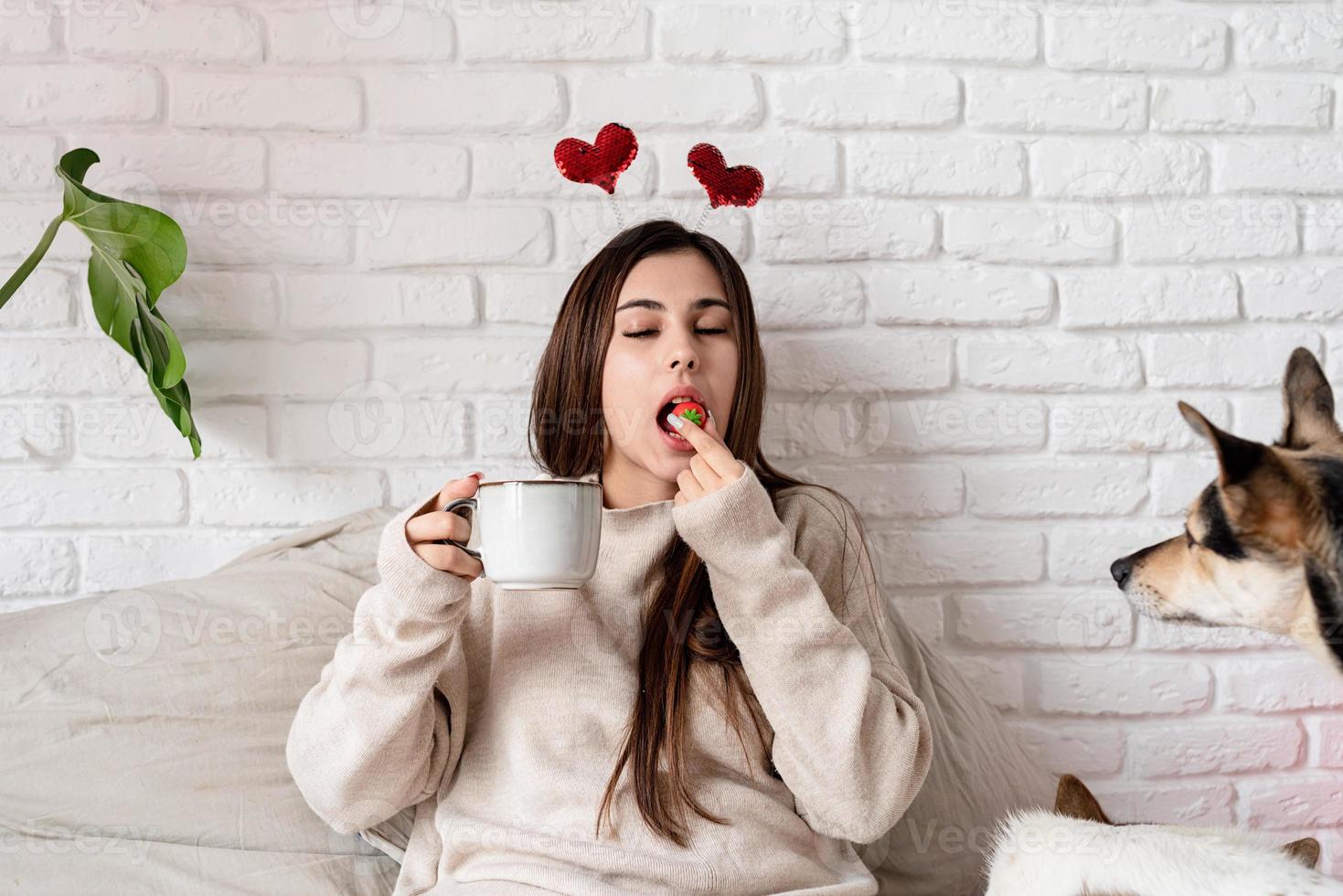 Valentine's day, Women's day. Young caucasian brunette woman sitting in the bed celebrating valentine day working on laptop online photo