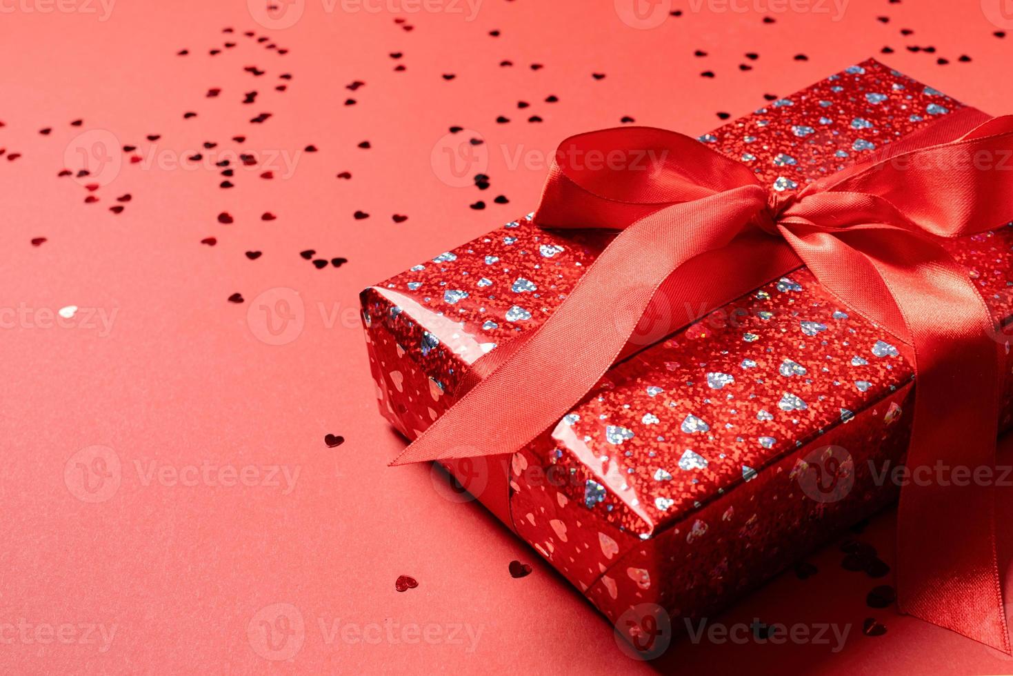 Red gift box with a ribbon for Valentines Day celebrating on red solid background with copy space photo