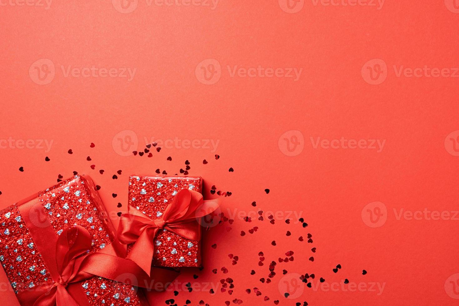 cajas de regalo rojas con cinta para el día de san valentín celebrando sobre fondo rojo sólido con espacio de copia foto