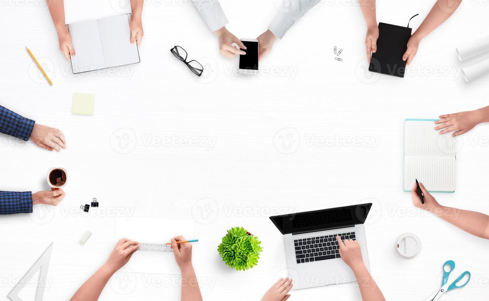 Company meeting. A desk with a top view of the hands of employees working on a computer and phone, taking notes, drawing a project and drinking a coffee concept. Empty space in the middle for text. photo