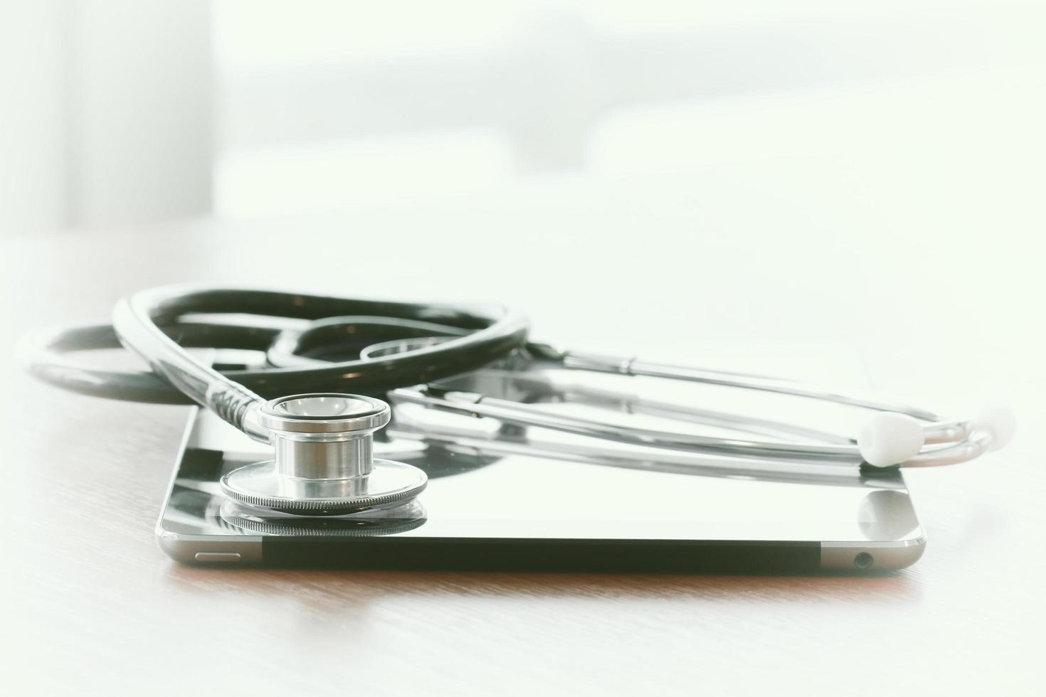 Studio macro of a stethoscope and digital tablet with shallow DOF evenly matched abstract on wood table background copy space photo