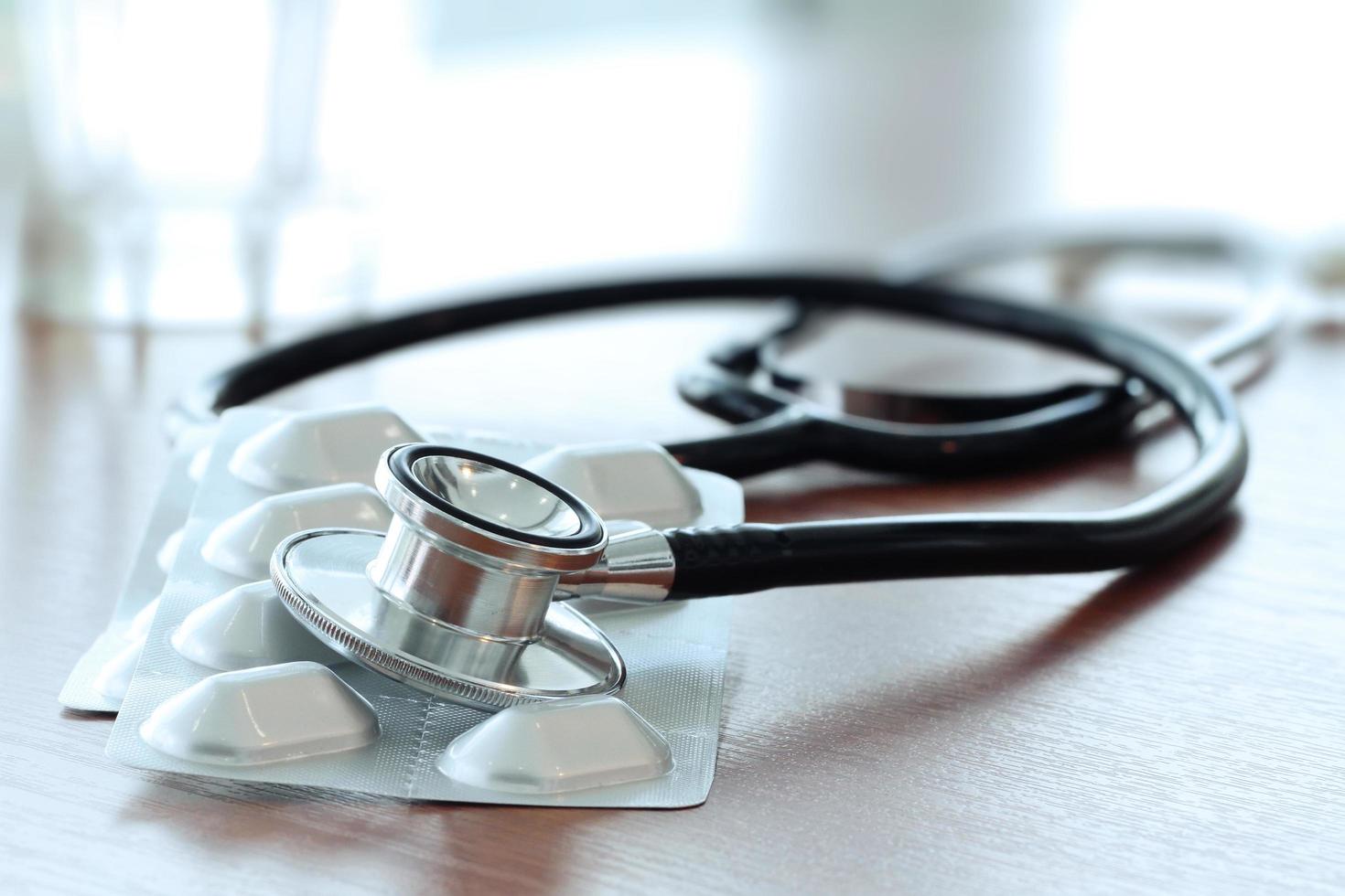 Studio macro of a stethoscope and pills with shallow DOF evenly matched abstract on wood table background copy space photo