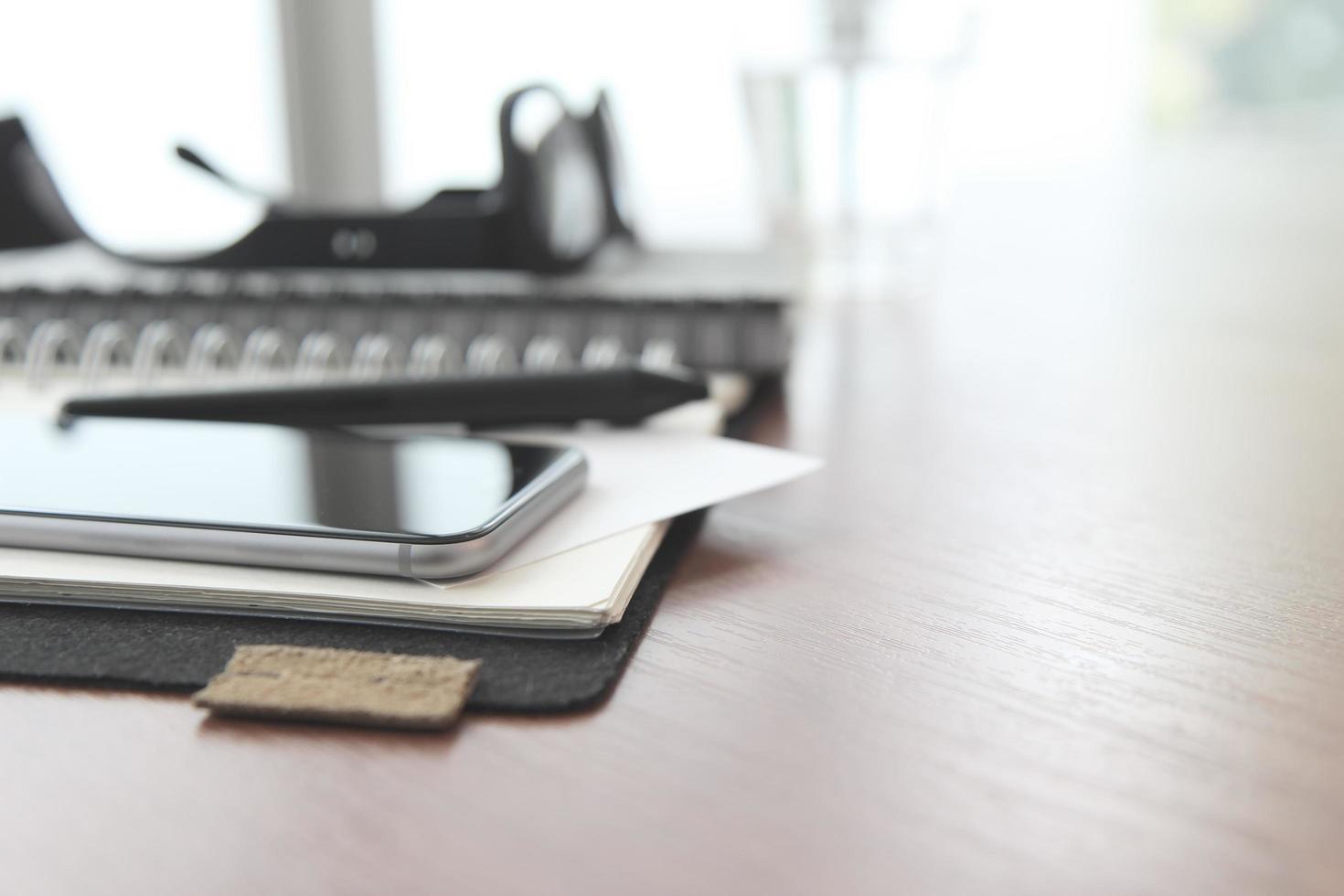 lugar de trabajo de oficina con computadora portátil y teléfono inteligente y lápiz en la mesa de madera foto