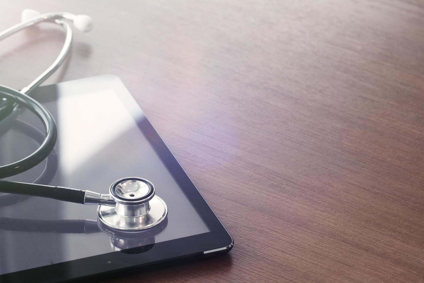 Studio macro of a stethoscope and digital tablet with shallow DOF evenly matched abstract on wood table background copy space photo