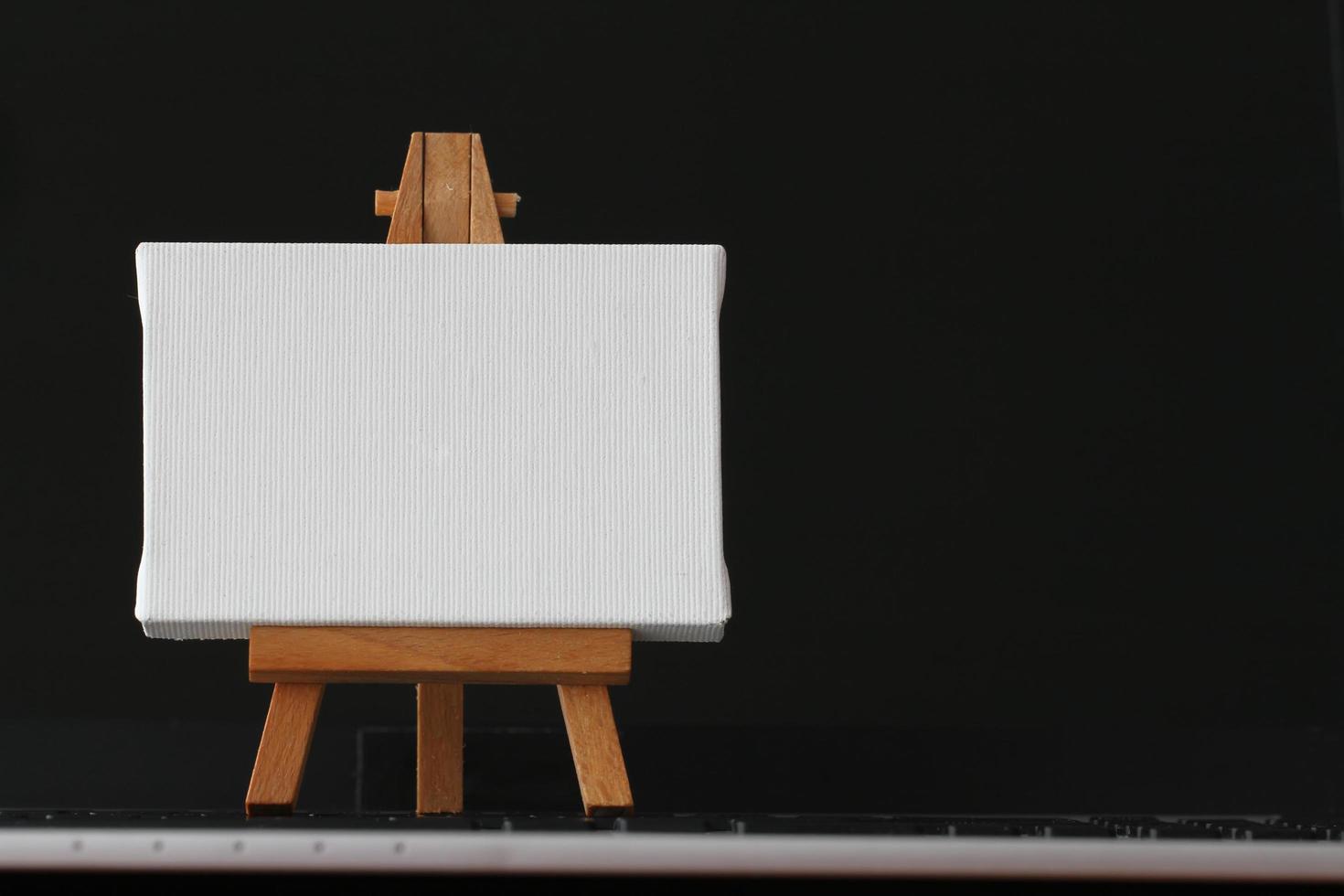 blank canvas and wooden easel on laptop computer as concept photo