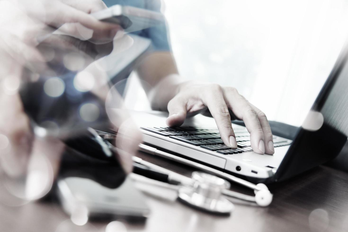 Abstract Image of Doctor working with laptop computer in medical workspace office and picking smart phone as concept photo