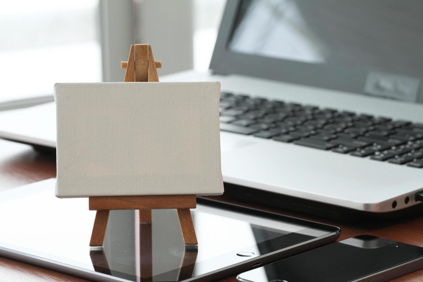 blank canvas and wooden easel on laptop computer as concept photo