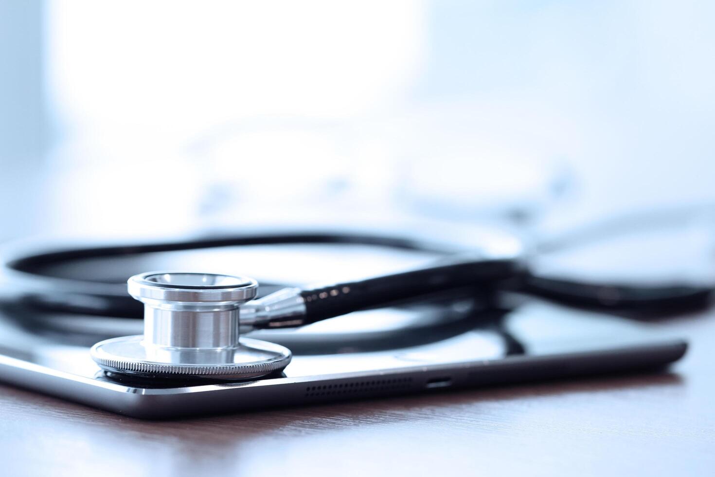 Studio macro of a stethoscope and digital tablet with shallow DOF evenly matched abstract on wood table background copy space photo