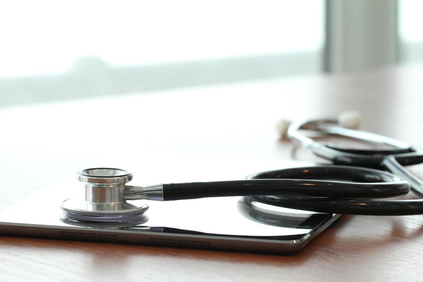 Studio macro of a stethoscope and digital tablet with shallow DOF evenly matched abstract on wood table background copy space photo