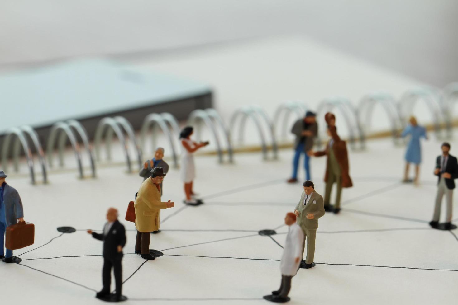 close up of miniature people with social network diagram on open notebook on wooden desk as social media concept photo