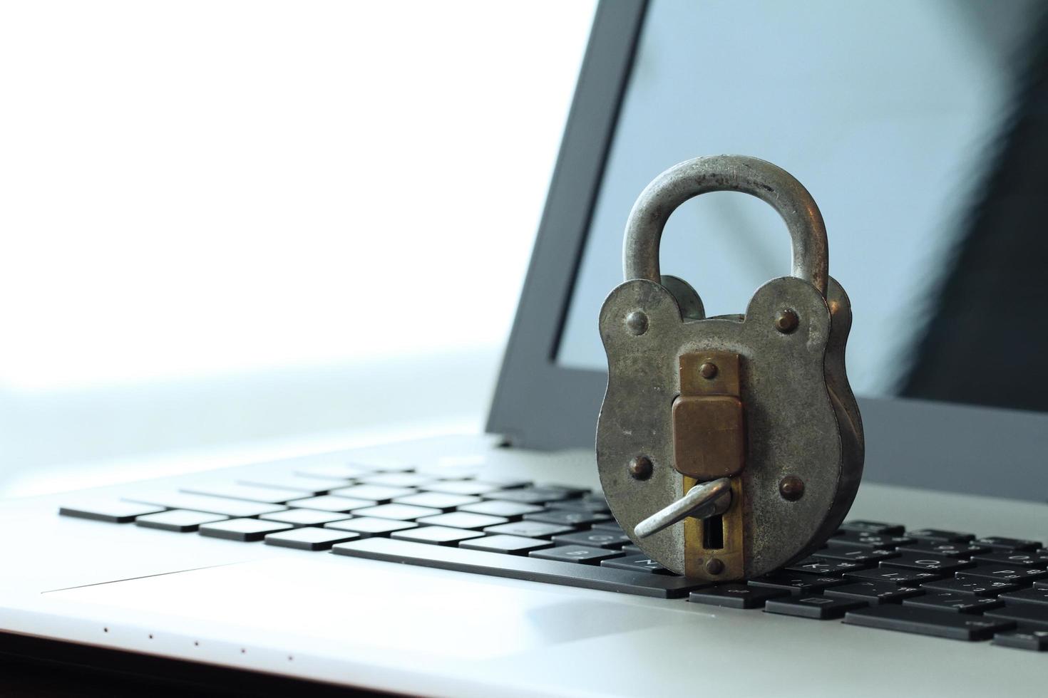 concepto de seguridad en Internet: candado antiguo y llave en el teclado de la computadora portátil foto