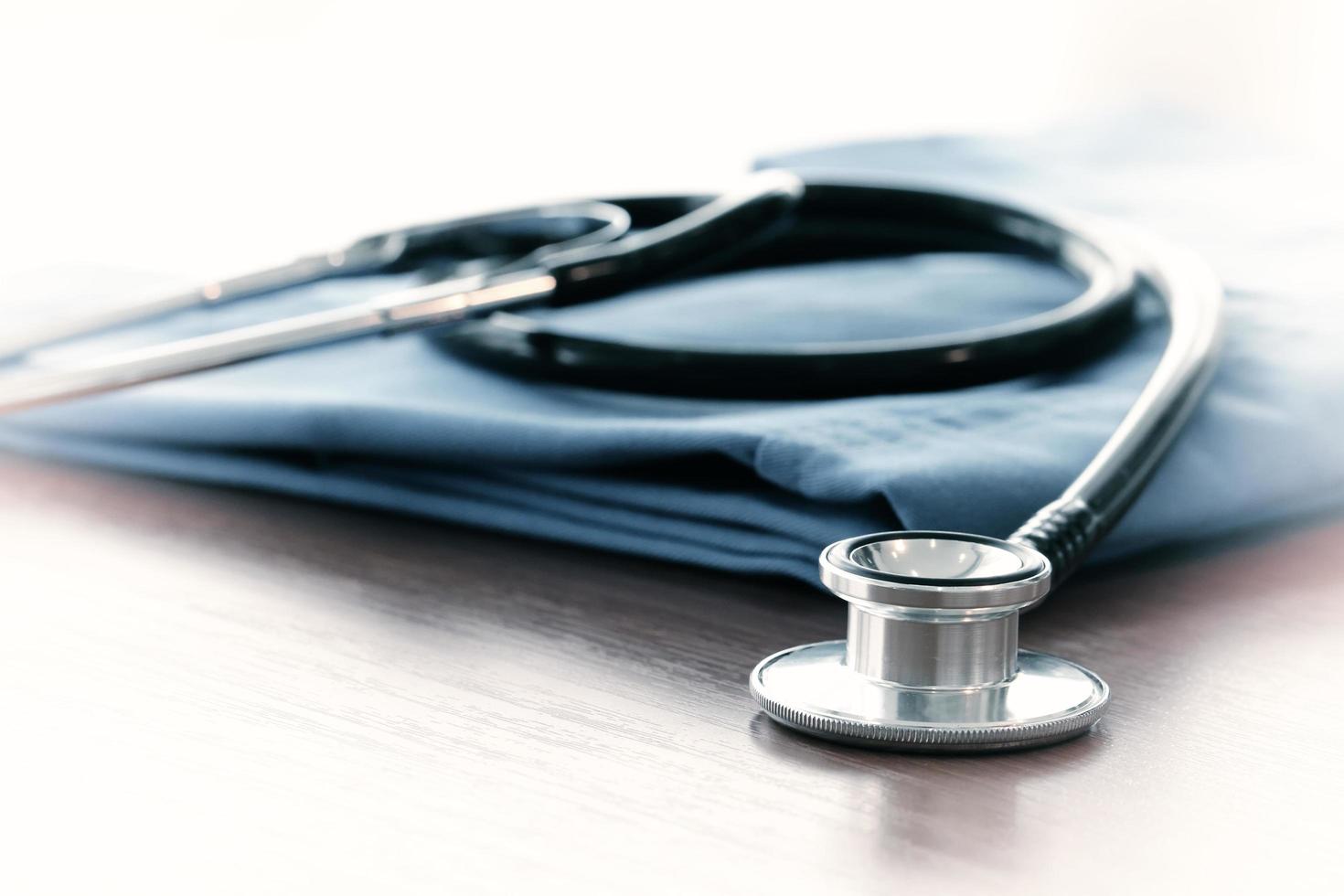 Stethoscope with blue doctor coat on wooden table with shallow DOF evenly matched and background photo