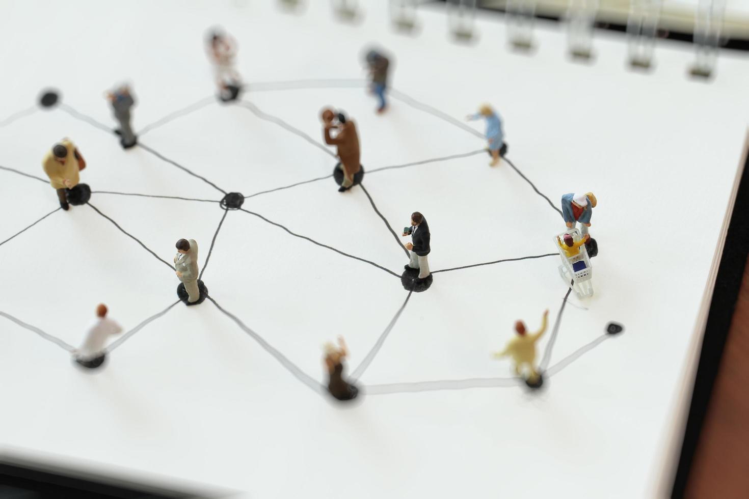 close up of miniature people with social network diagram on open notebook on wooden desk as social media concept photo