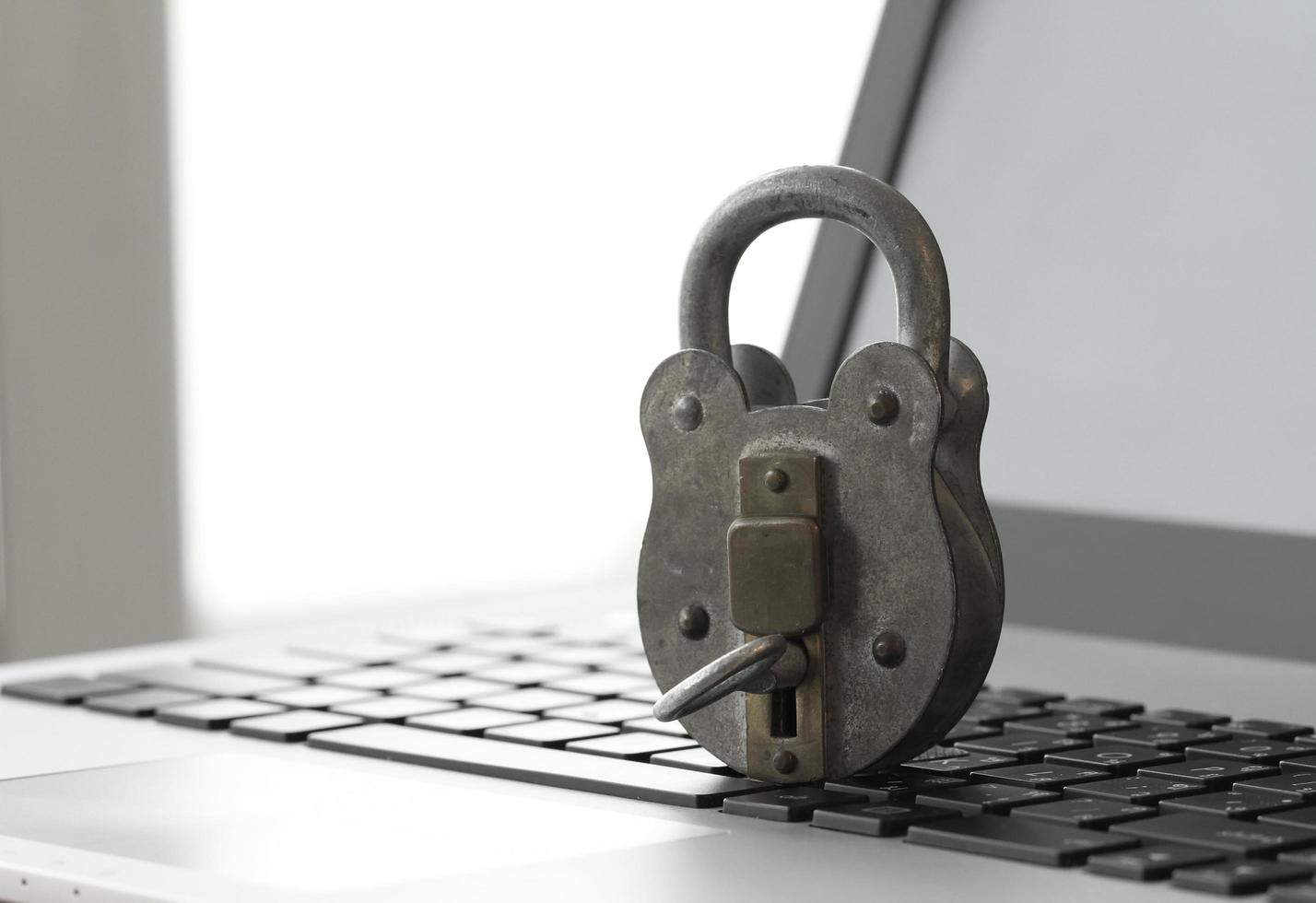 Internet security concept-miniature businessman stand on old key and padlock on laptop computer keyboard photo