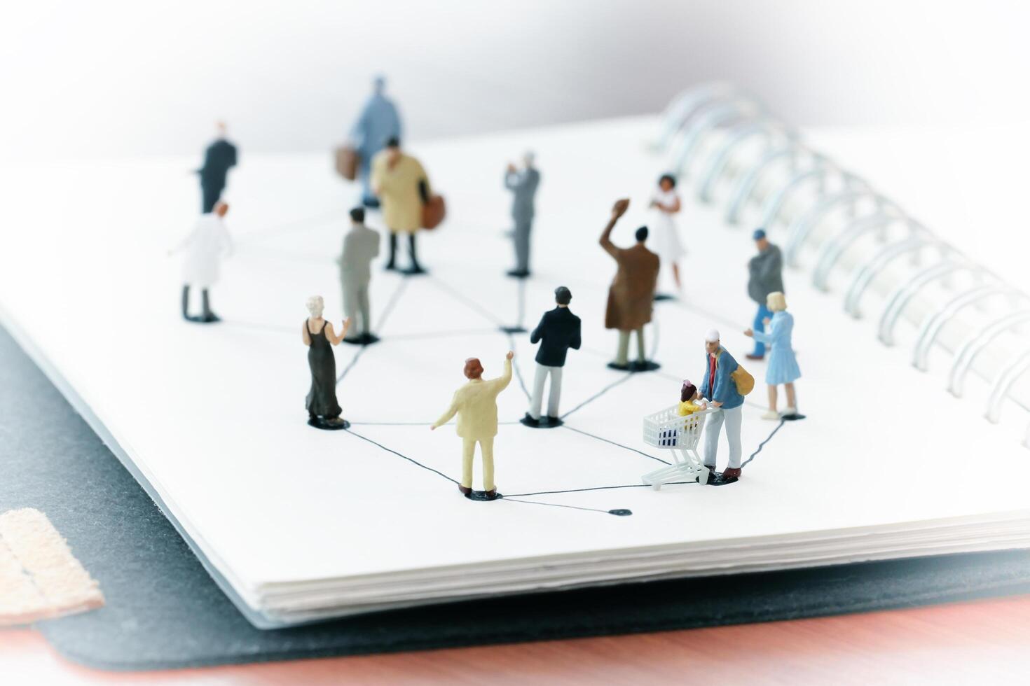 close up of miniature people with social network diagram on open notebook on wooden desk as social media concept photo