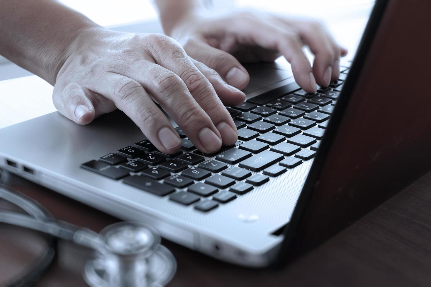 close up of Doctor hand using laptop computer in office photo