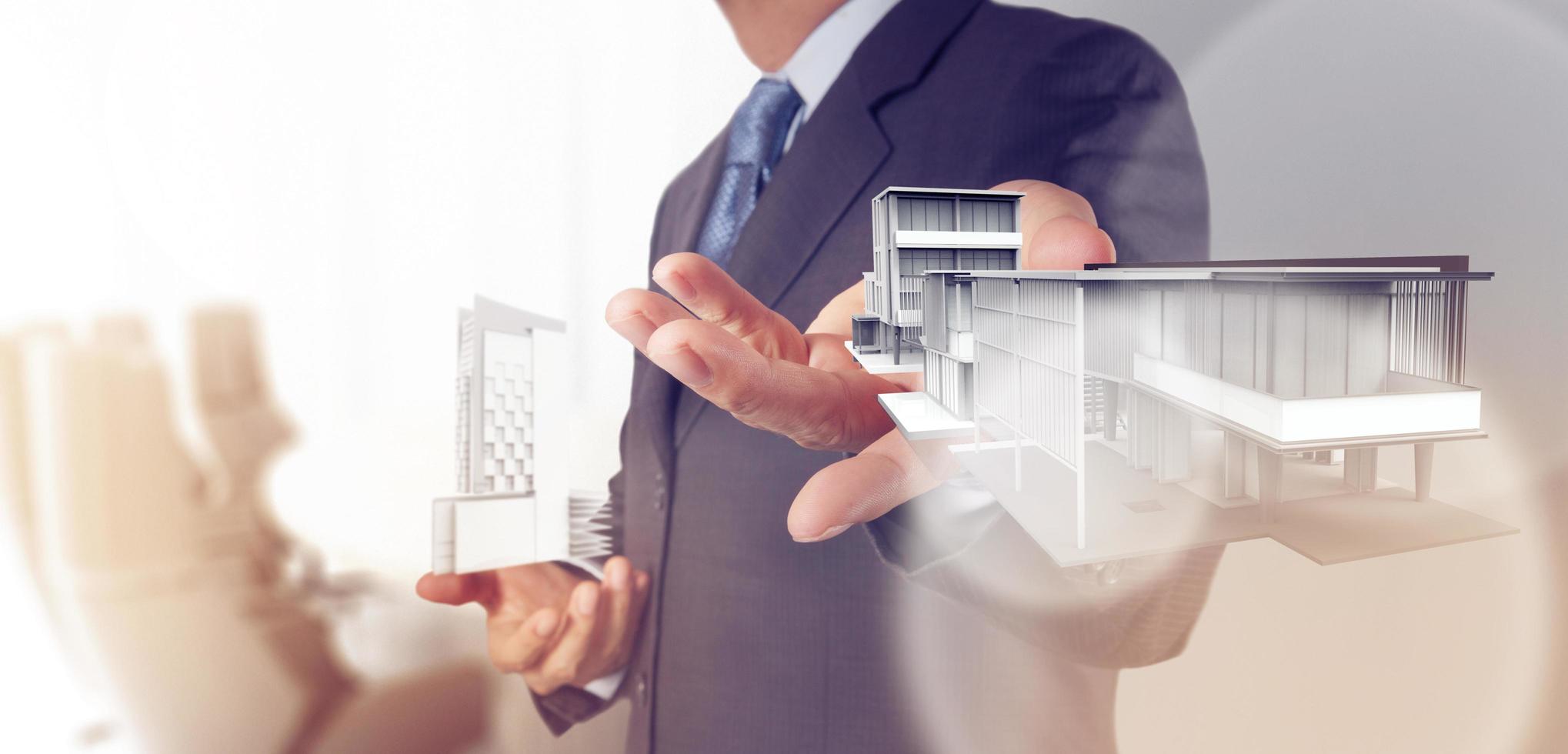 businessman hand presents house model on modern computer photo
