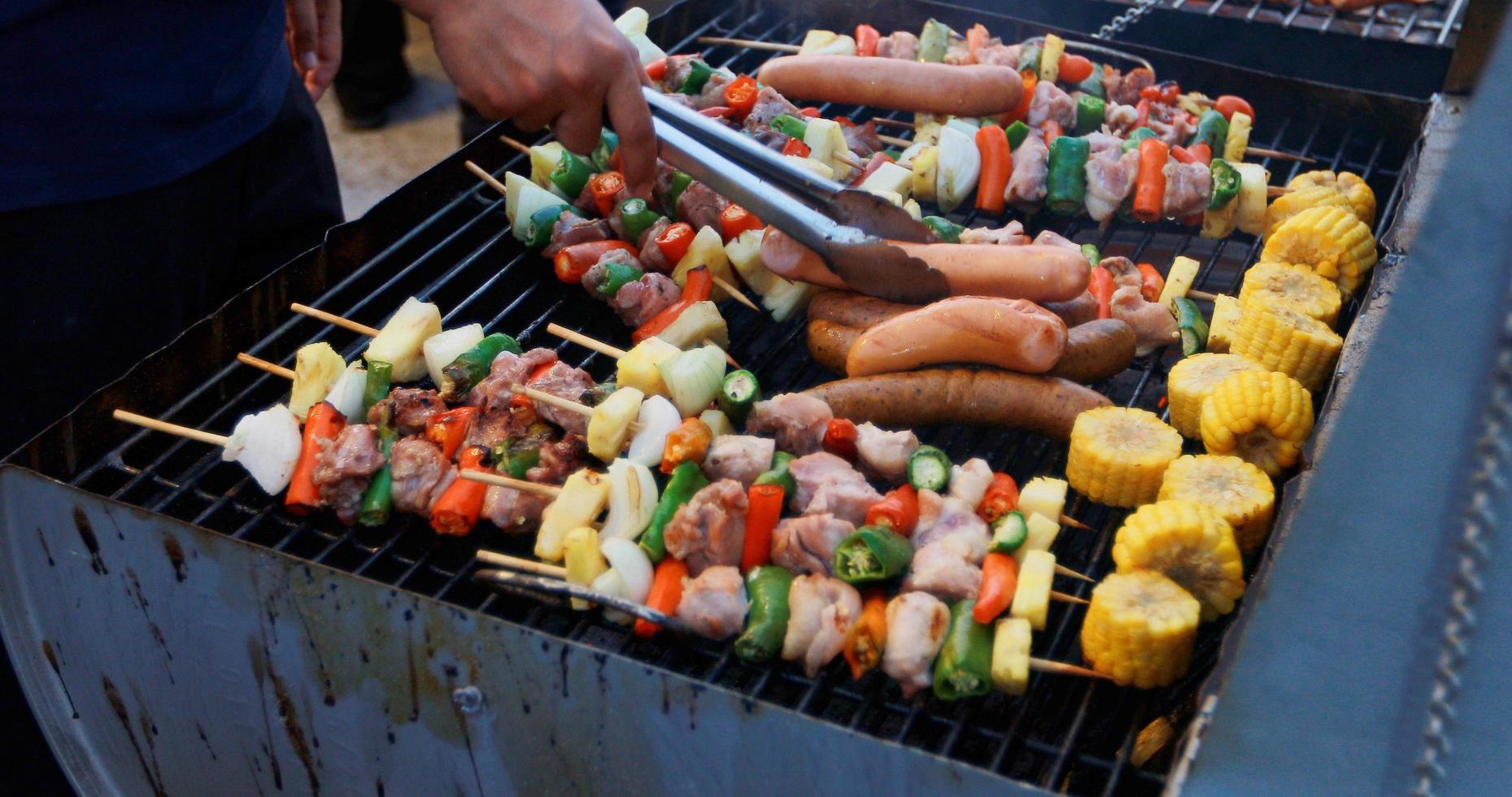 Grupo asiático de amigos con barbacoa en el jardín al aire libre riendo con bebidas alcohólicas de cerveza en la noche foto