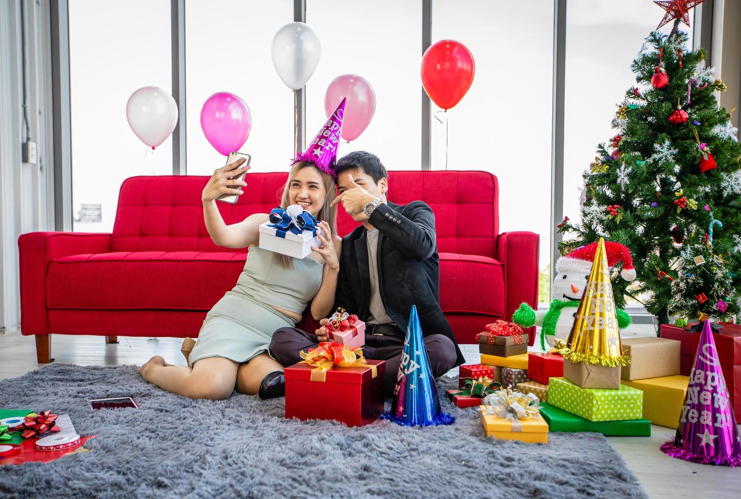 pareja asiática amante está dando una caja de regalo y tomando una selfie por teléfono inteligente móvil con regalo de navidad en vacaciones de navidad y feliz patty de año nuevo foto