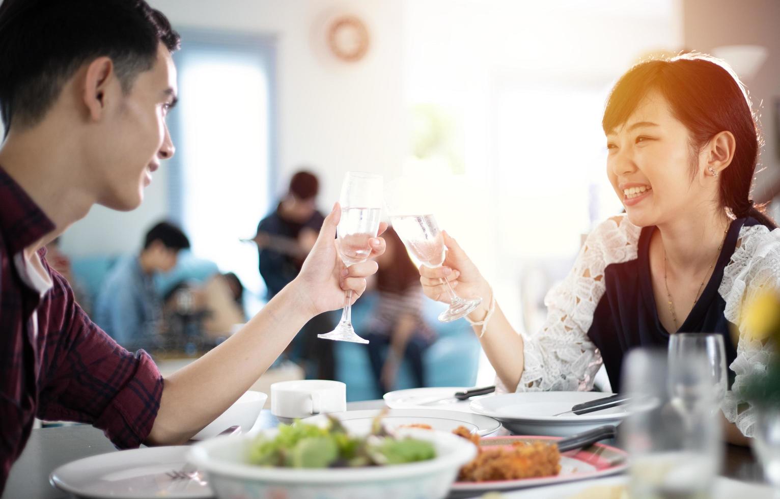 Asian young couple enjoying a romantic dinner  evening drinks while sitting at the dinning table on the kitchen together photo