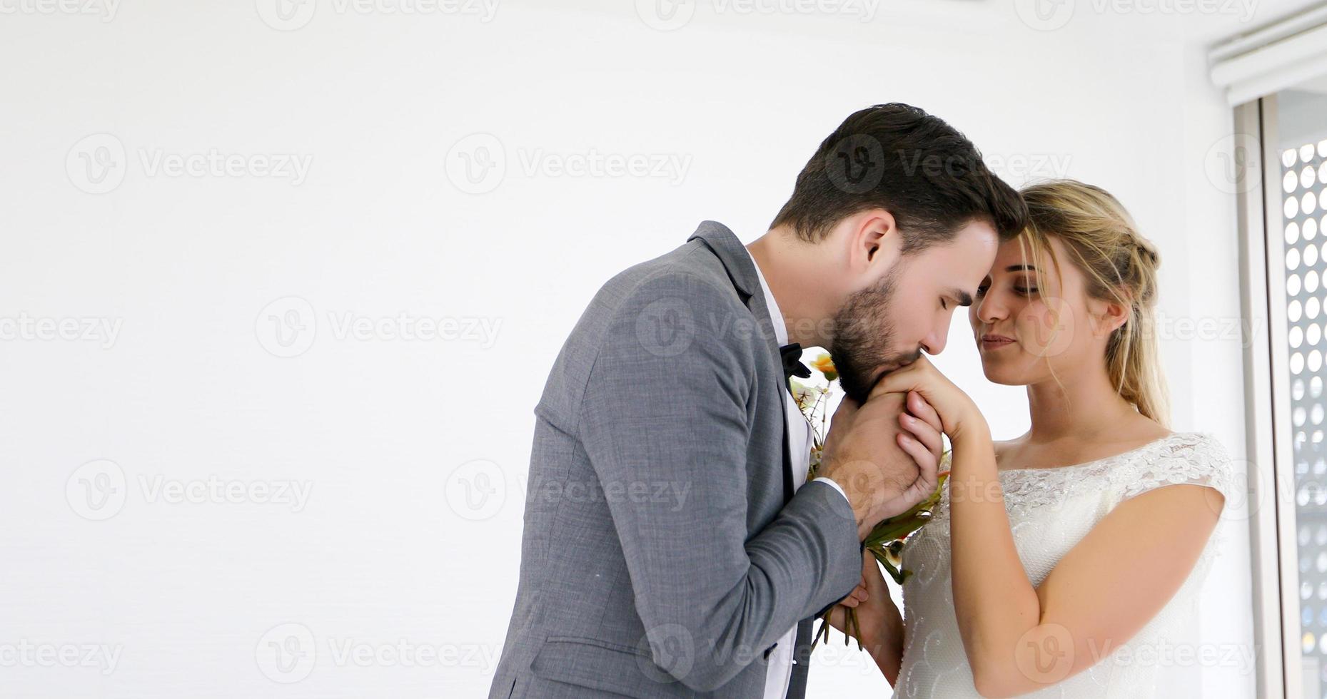 The lovers give flowers to the bride and kissed happy and couple love standing in wedding studio photo