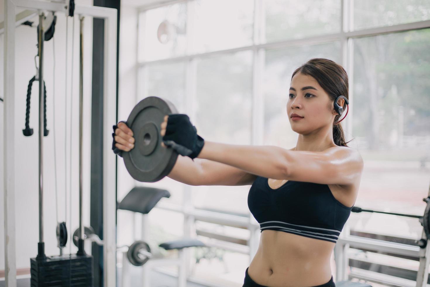 hermosa mujer en forma muscular ejercicio de construcción de músculos y fitness mujer haciendo ejercicios en el gimnasio. fitness - concepto de estilo de vida saludable foto