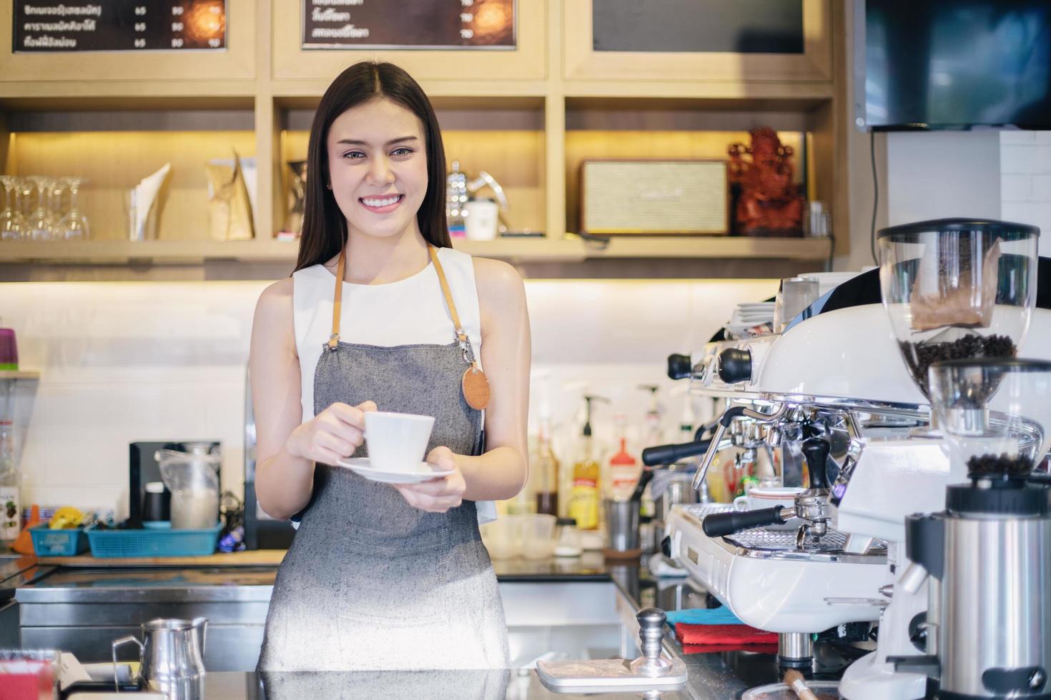 Las mujeres asiáticas barista sonriendo y usando la máquina de café en el mostrador de la cafetería - mujer trabajadora propietario de una pequeña empresa comida y bebida concepto de cafetería foto