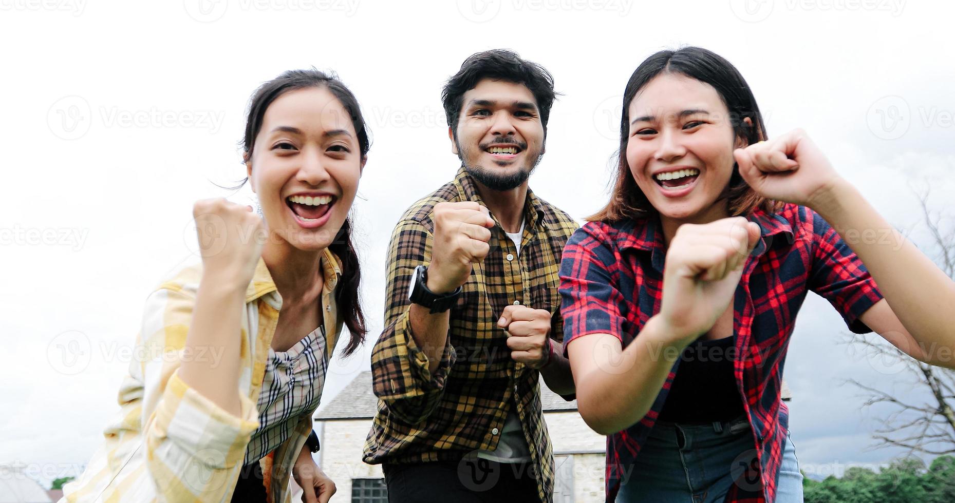 Successful Young students at campus looking at camera and smiling and high five while jumping on outdoors. photo