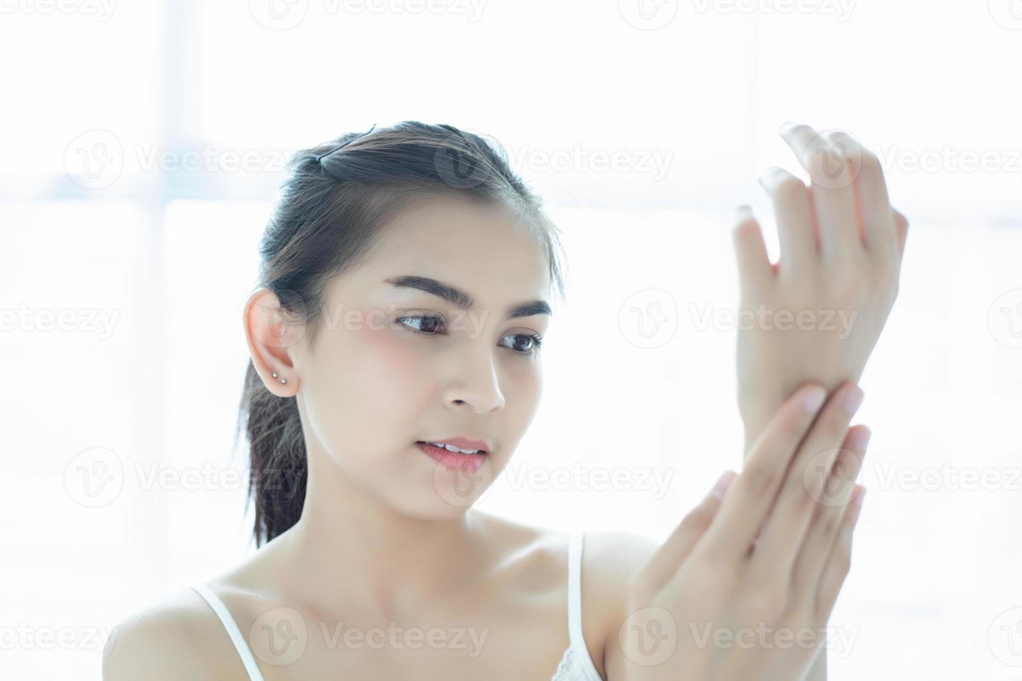 una hermosa mujer asiática que usa un producto para el cuidado de la piel, crema hidratante o loción para cuidar su cutis seco. crema hidratante en manos femeninas. foto