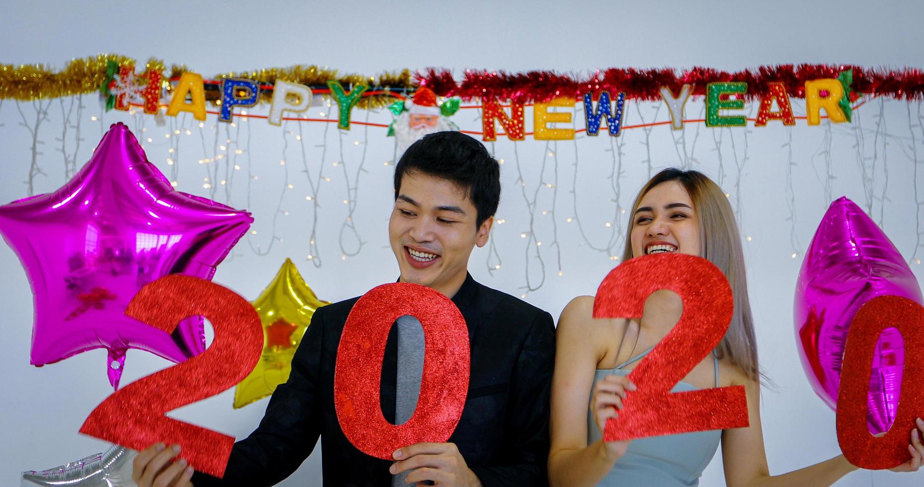 amante de la pareja asiática con números de 2020 celebrando un año nuevo en un bar gritando y riendo y contando hasta la medianoche en una fiesta de año nuevo foto