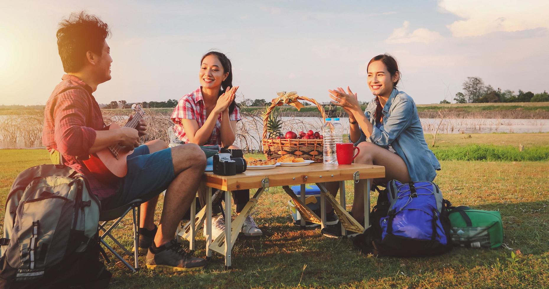 A group of Asian friends playing Ukelele and spending time making a picnic in the summer holidays.They are happy and have fun on holidays. photo