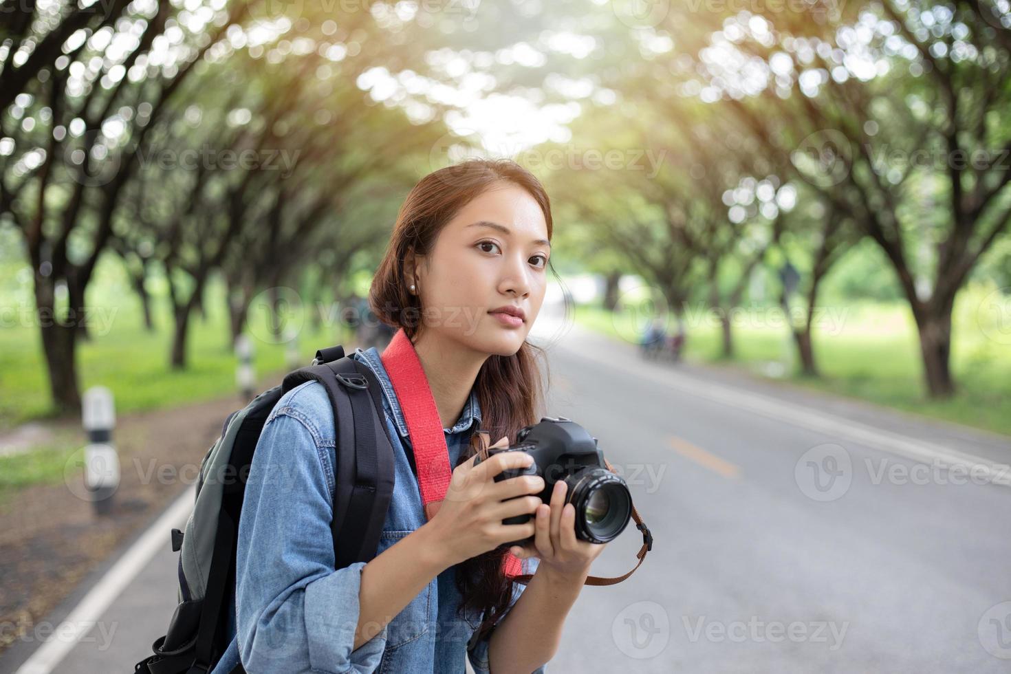 mujer fotógrafa sosteniendo una cámara en la naturaleza para tomar una foto del viajero turístico