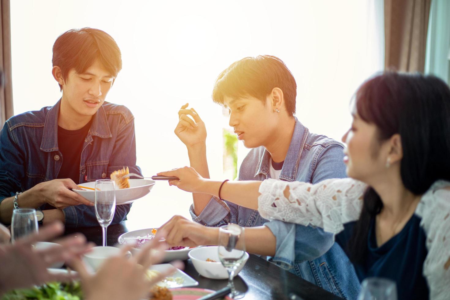 Dinner with Asian Group of best friends enjoying evening drinks while sitting at the dinning table on the kitchen together photo