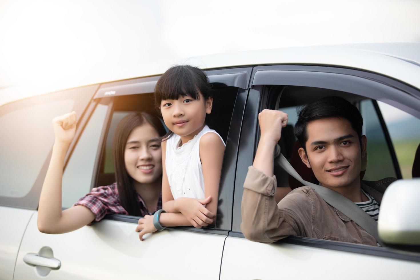 Happy little girl  with asian family sitting in the car for enjoying road trip and summer vacation in camper van photo