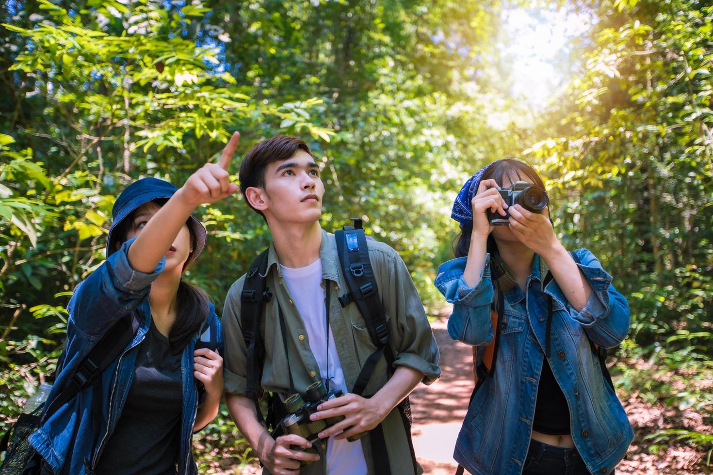 Asian Group of young people Hiking with friends backpacks walking together and looking map and taking photo camera by the road and looking happy ,Relax time on holiday concept travel