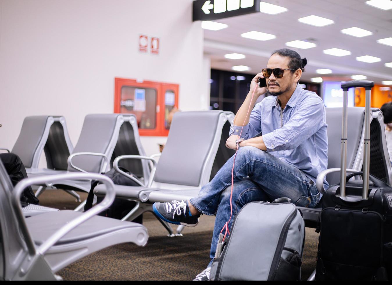 Asian man with backpack  traveler using the smart mobile phone for Video call and taking at an airport,Blurry and soft focus photo
