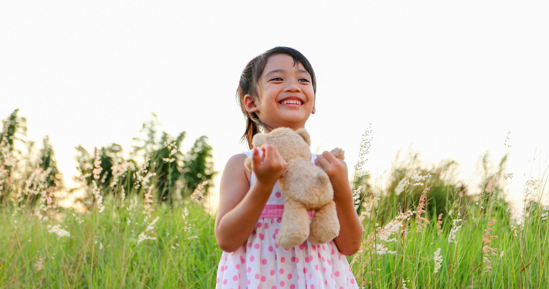 Asian  Girls playing teddy bears and laughing happy on meadow in summer in nature photo