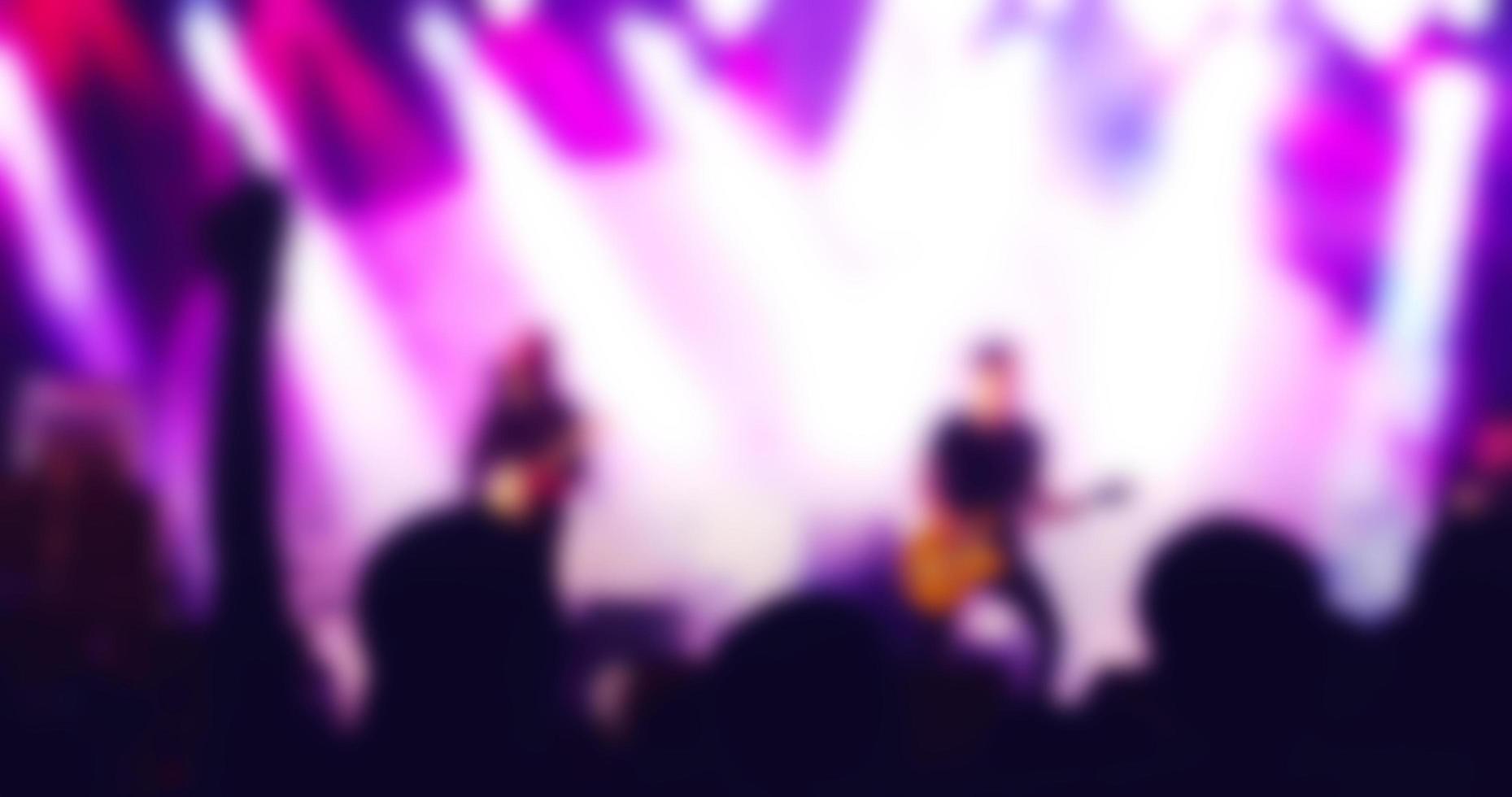 silhouettes of concert crowd at Rear view of festival crowd raising their hands on bright stage lights photo