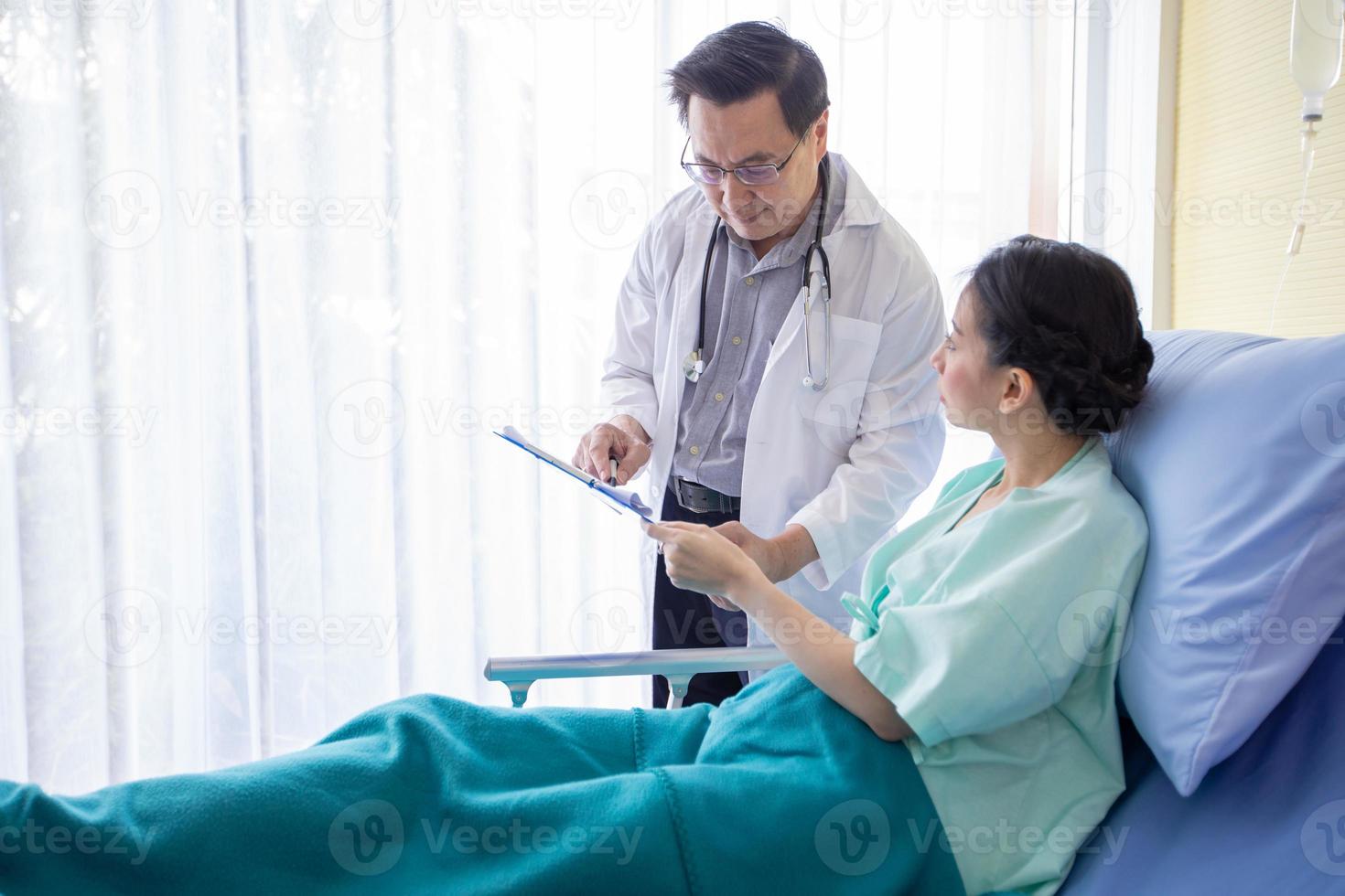 los médicos preguntan y explican sobre la enfermedad a una paciente acostada en la cama de un hospital. foto