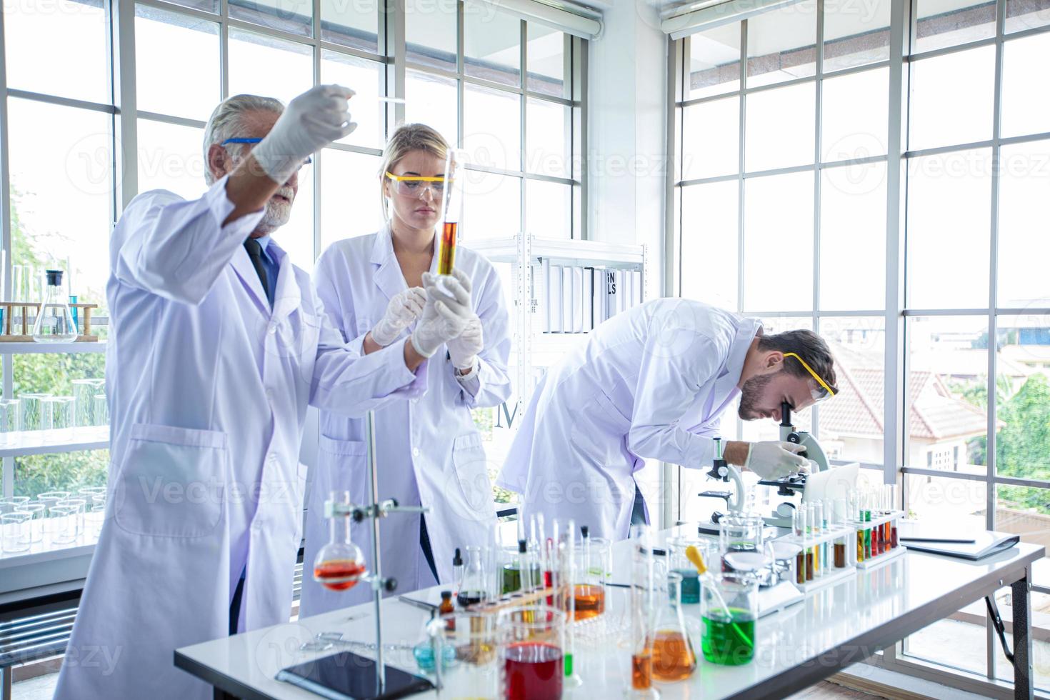 La investigación médica y los científicos están trabajando con un microscopio y una tableta y tubos de ensayo, micropipetas y resultados de análisis en un laboratorio. foto