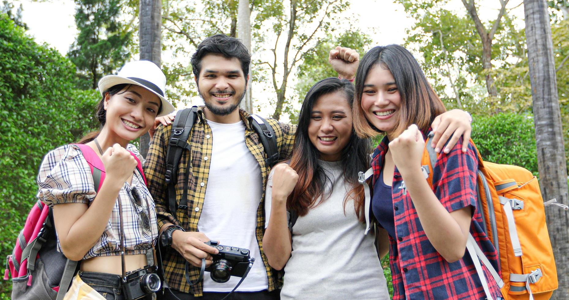 Asian Group of young people with friends backpacks walking together and happy friends are raised arms and enjoying a beautiful nature and cheering ,Relax time on holiday concept travel photo