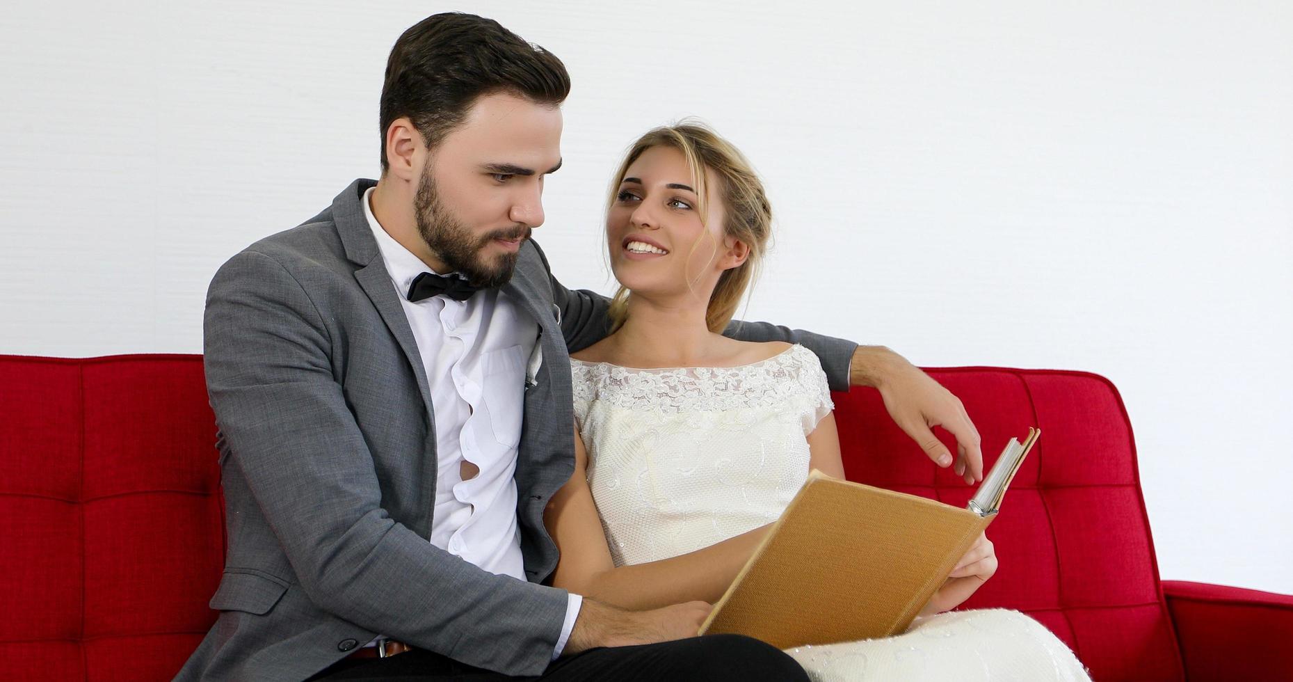 los amantes le dan flores a la novia y se besan felices y la pareja ama de pie en el estudio de bodas foto