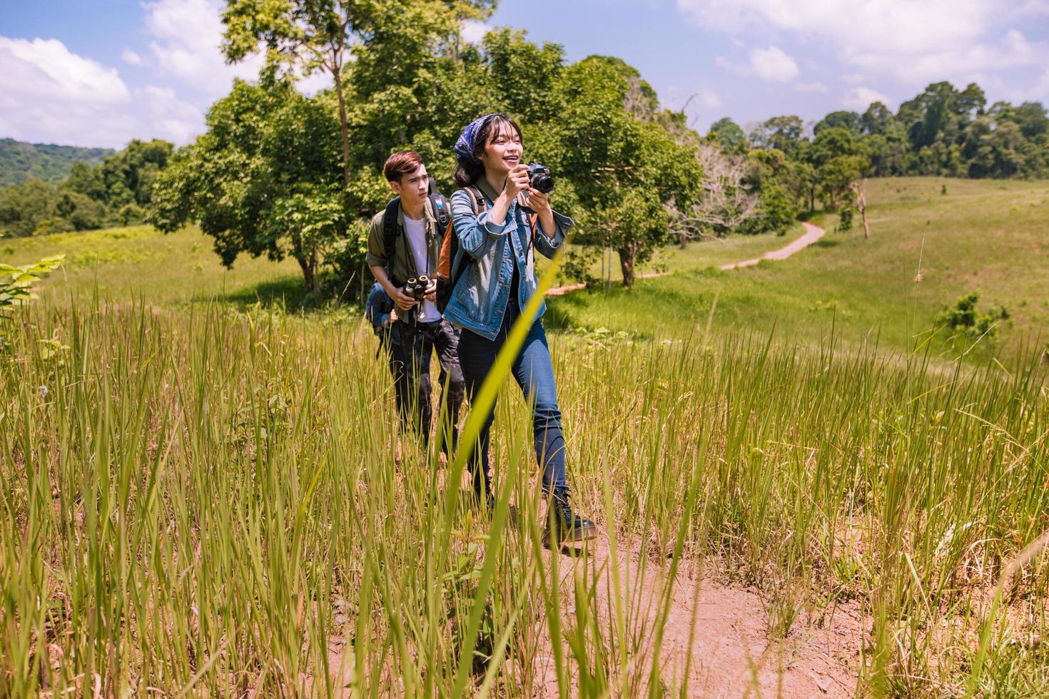 Asian Group of young people Hiking with friends backpacks walking together and looking map and taking photo camera by the road and looking happy ,Relax time on holiday concept travel
